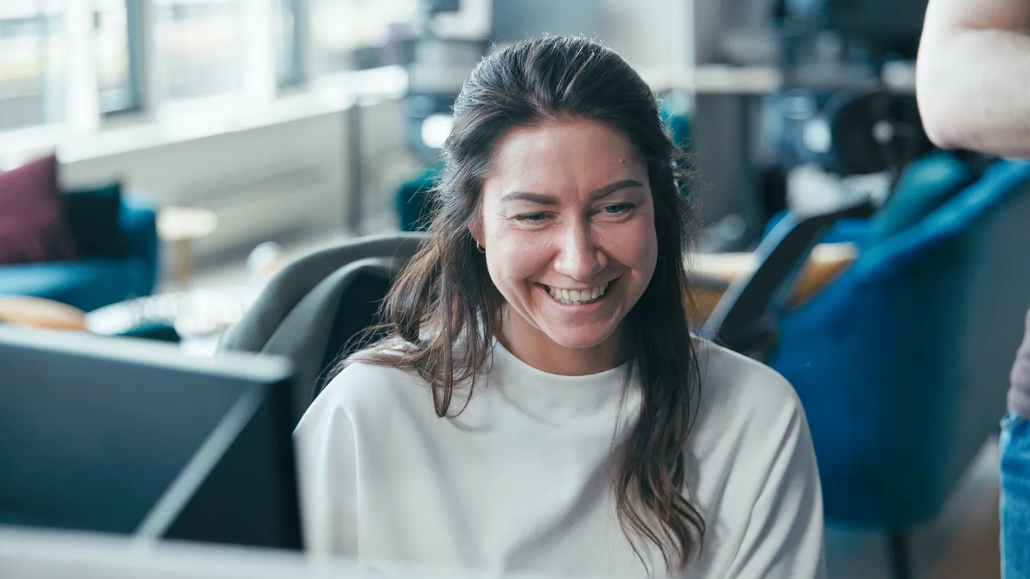 A colleague smiling at her desk in the open office